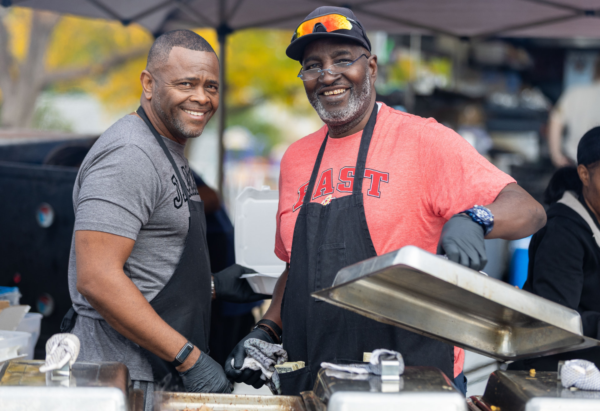 Kenny and Bruce smiling behind the serving pans at a vending event
