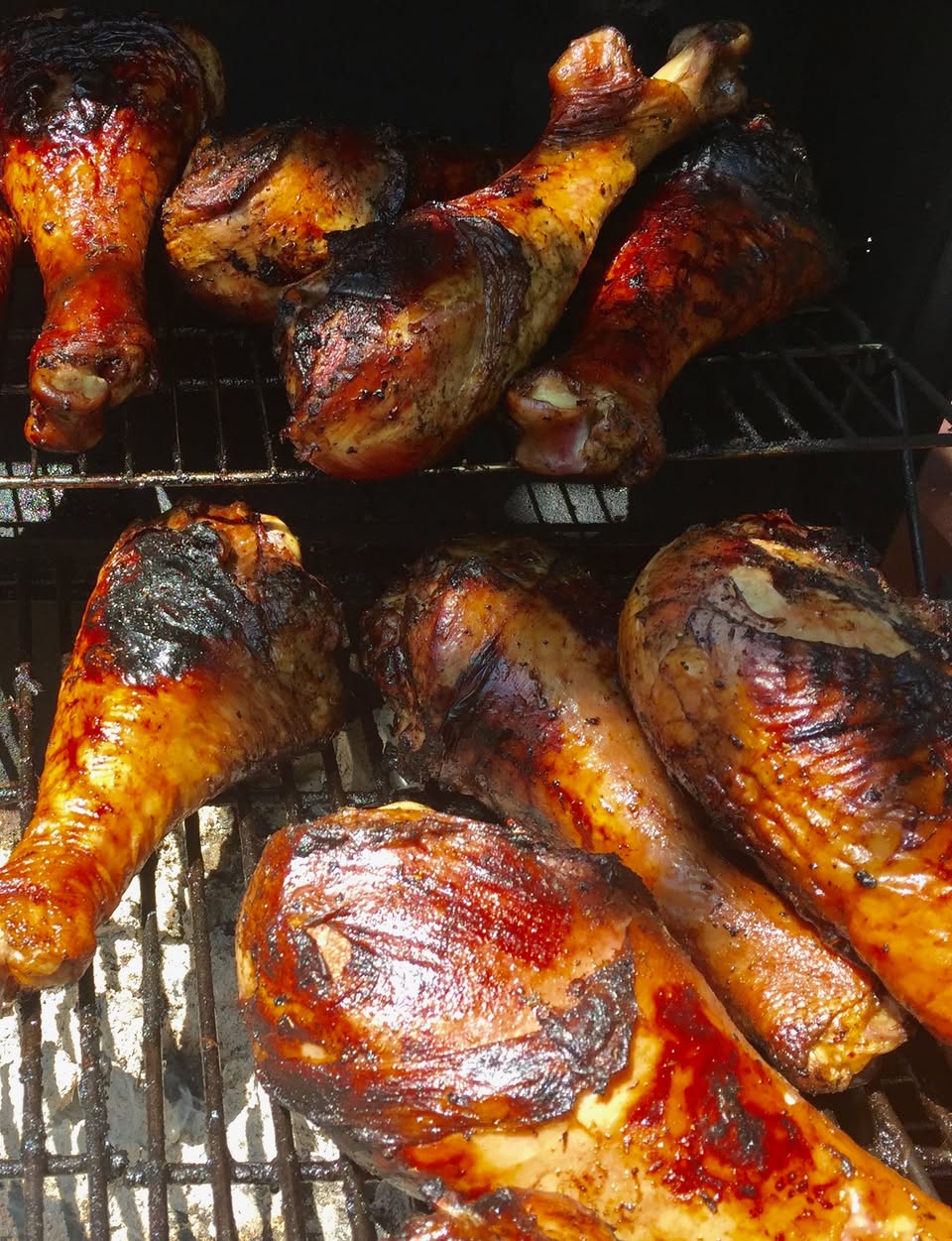 Glazed smoked turkey legs resting on the smoker grates