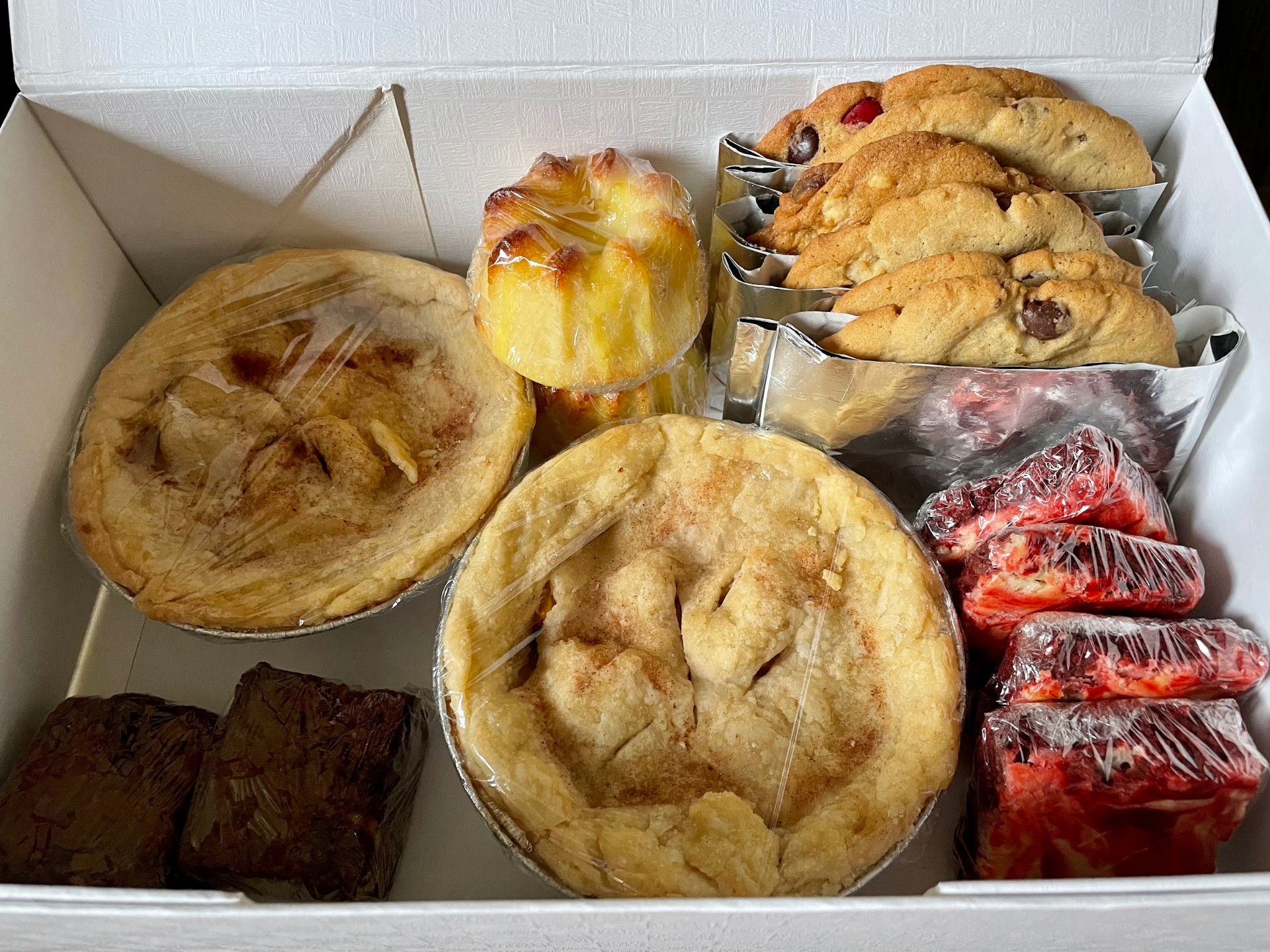 Box of homemade baked goods: pies, cookies, brownies and red velvet cake