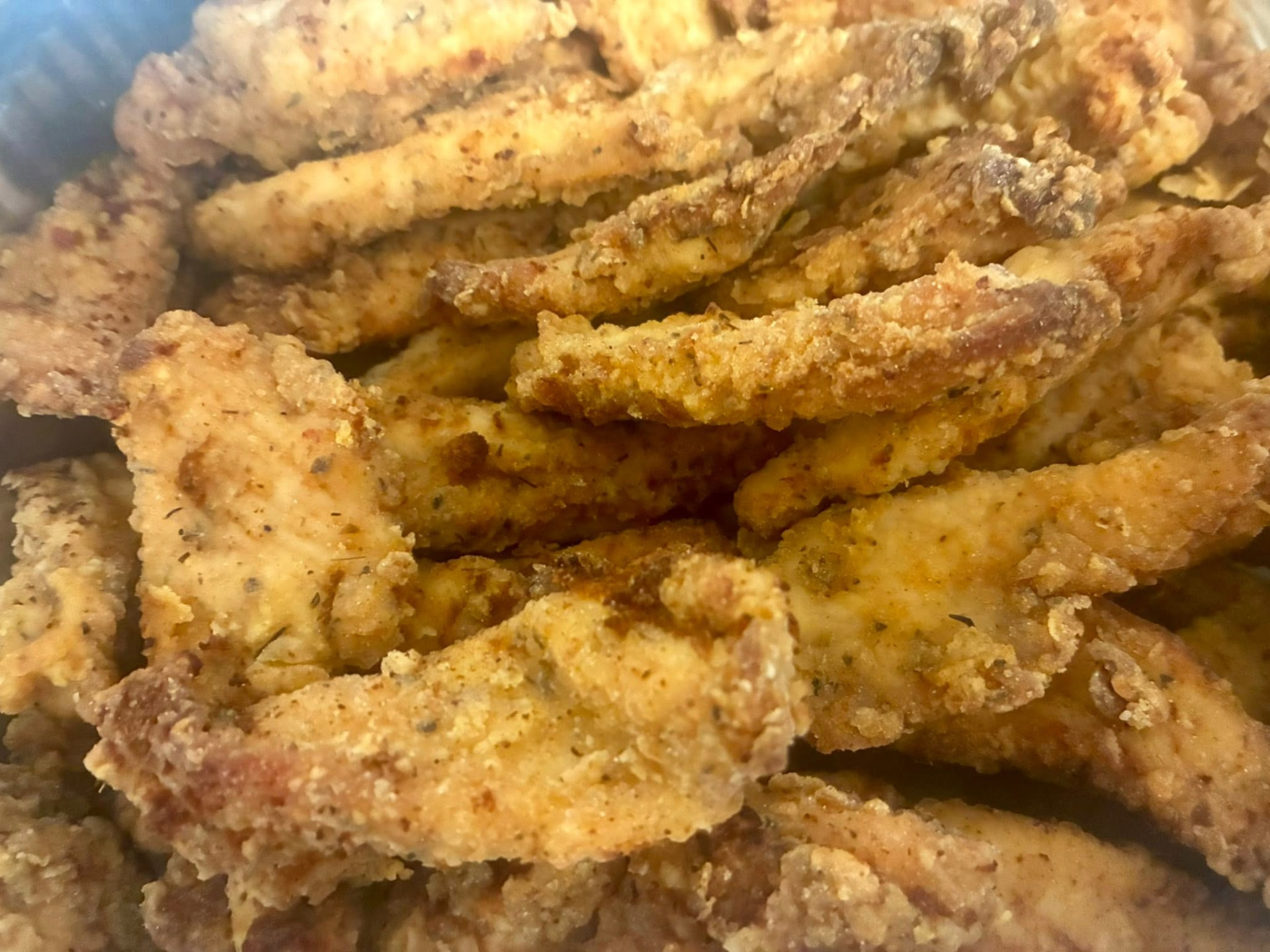 Golden seasoned fried chicken tenders fresh out of the fryer
