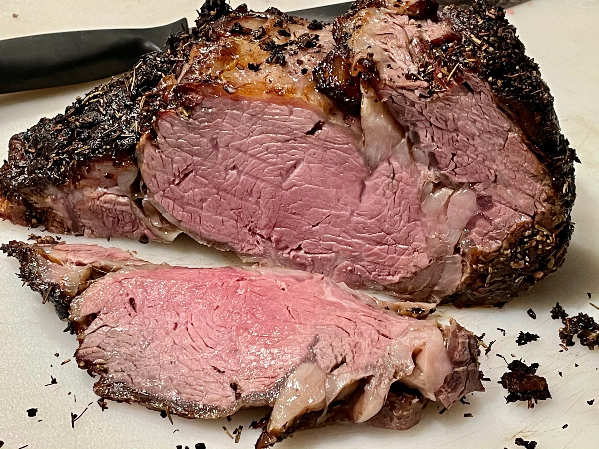 Herb-crusted smoked prime rib, sliced to reveal a rosy medium-rare center