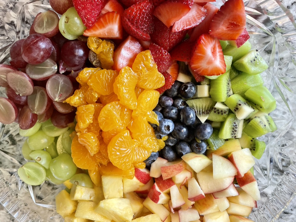 Crystal bowl of fresh cut fruit — strawberries, grapes, oranges, blueberries, kiwi, apples, pineapple