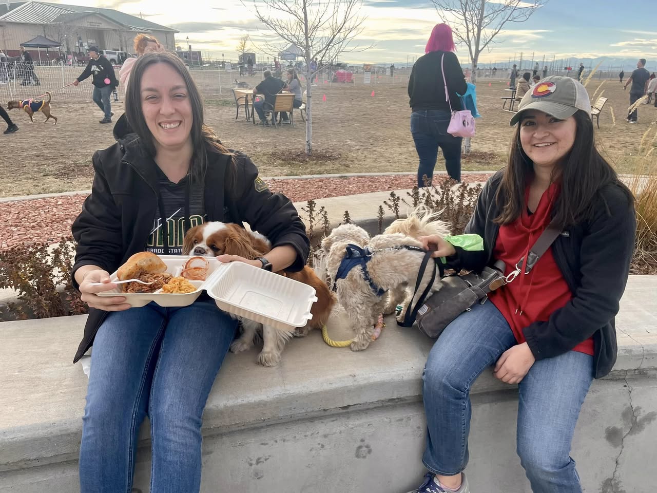 Guests with their dogs enjoying pulled pork sandwiches and mac & cheese at an outdoor festival