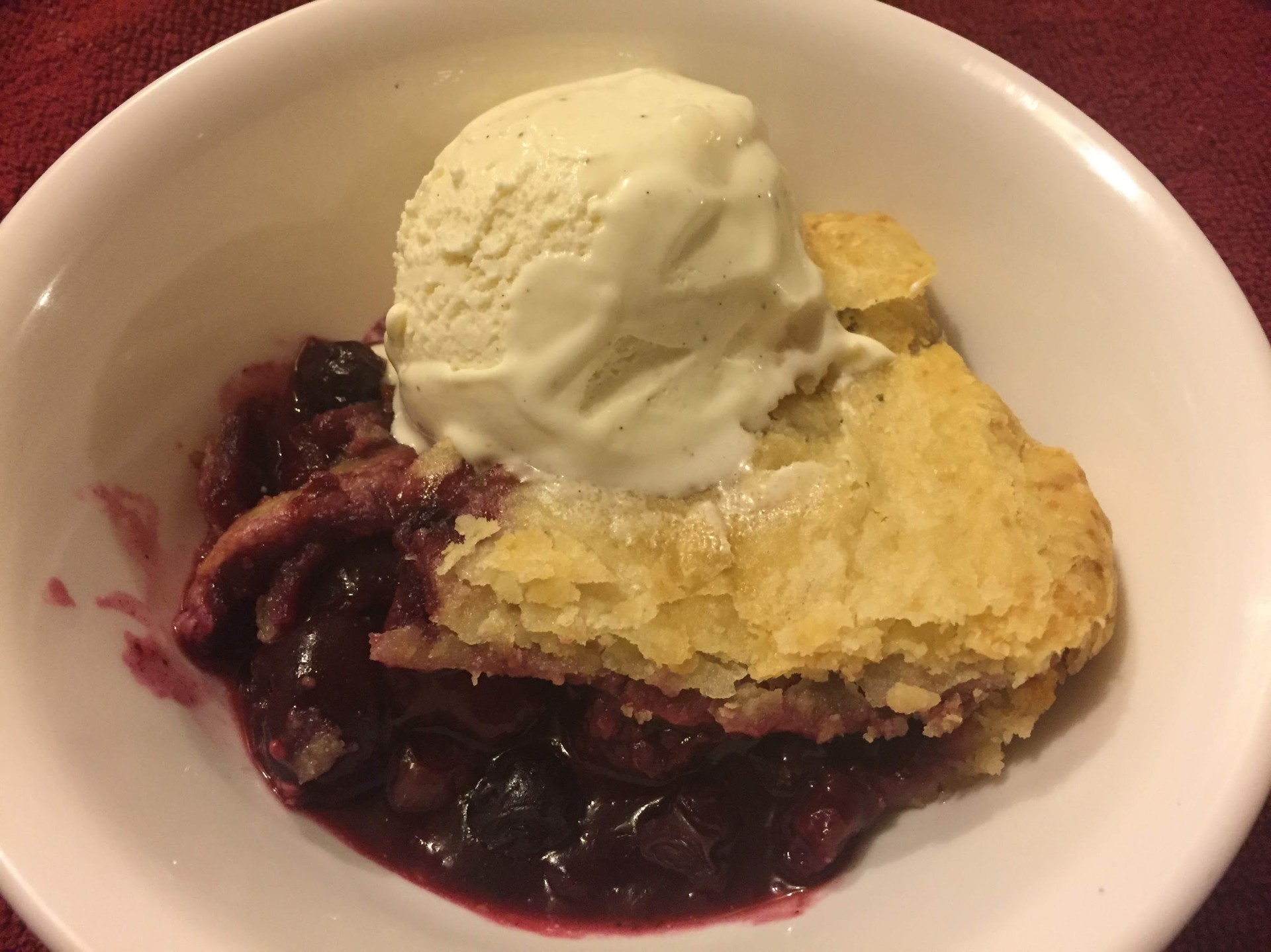 Warm berry cobbler topped with a scoop of vanilla ice cream